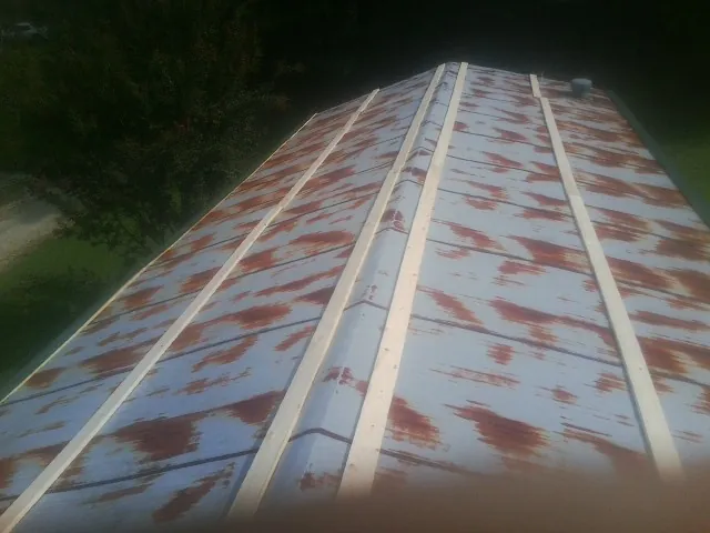 Rusted metal roof panels with new wood purlins before replacement — Storm Damage Roof Repair in Table Grove by Roofing Brothers
