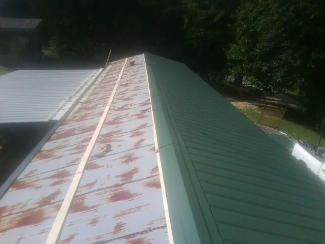 Old rusted panels beside newly installed green metal roofing — Wind Damage Roof Repair by Roofing Brothers in Table Grove