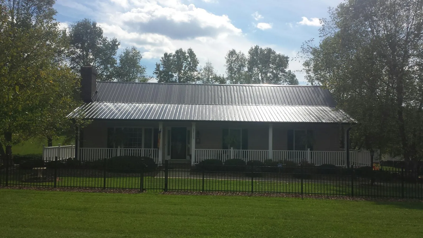 Gray metal roof on a brick ranch with a full width front porch — Gutter Guard Installation work by our crew in Table Grove